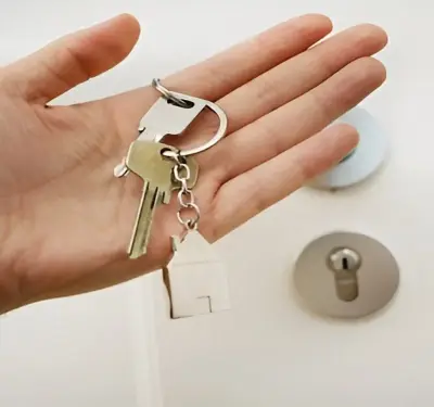 Hand holding house keys in front of a door